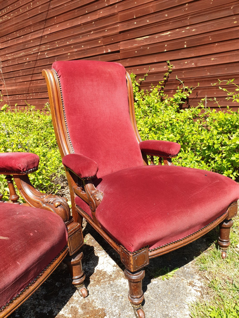 A pair of Victorian armchairs upholstered in crimson red velvet with turned wooden spindle armrests and brass castors. View III