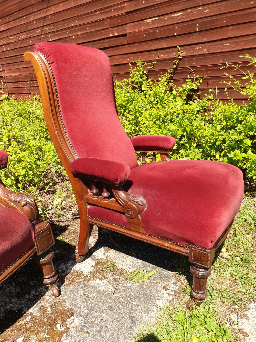 A pair of Victorian armchairs upholstered in crimson red velvet with turned wooden spindle armrests and brass castors. View IV