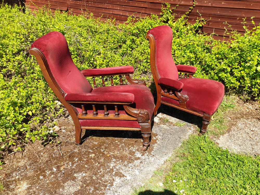 A pair of Victorian armchairs upholstered in crimson red velvet with turned wooden spindle armrests and brass castors. View VI