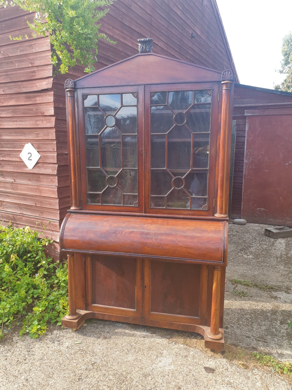 A Regency mahogany bureau bookcase featuring a pediment roof, two glazed cabinet doors with geometric astragal bars, a drop-down desk flap revealing interior drawers, and a lower double-door cupboard flanked by turned side columns. View III