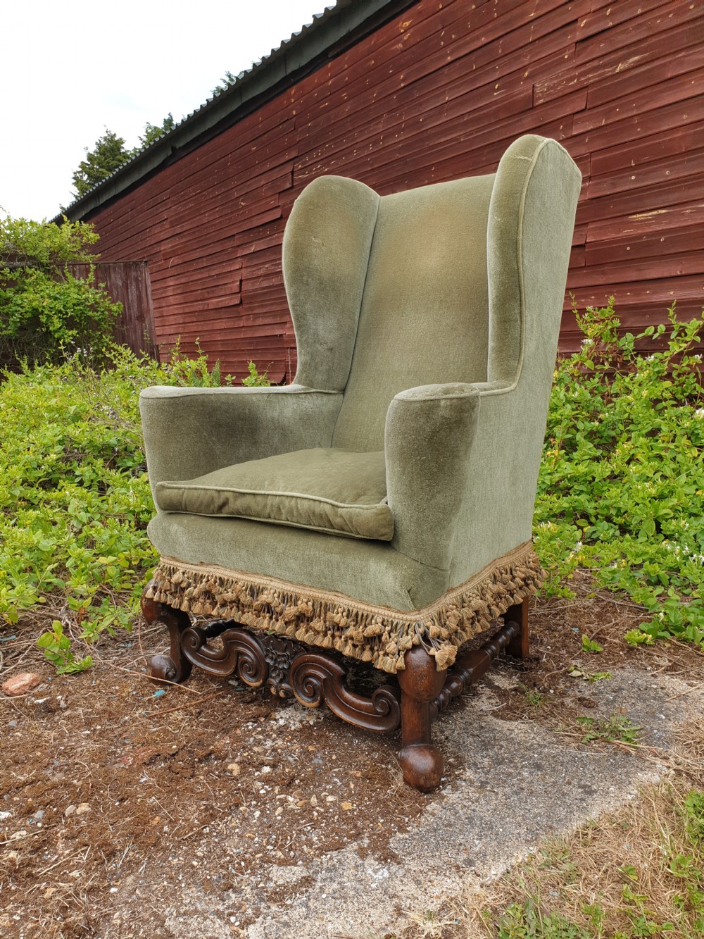Upholstered wing back armchair of Queen Anne design. 
