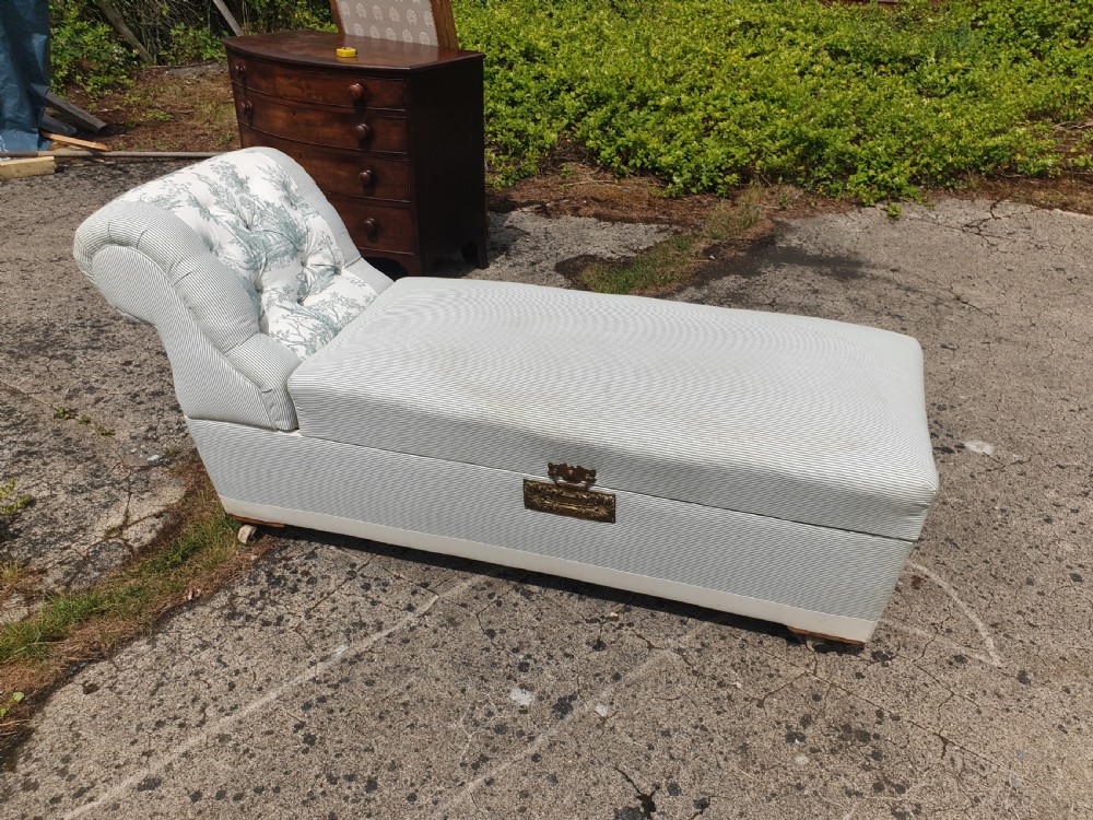 A late Victorian box ottoman chaise longue upholstered in grey and white ticking stripe fabric featuring a button-tufted backrest and a brass front latch. View IV