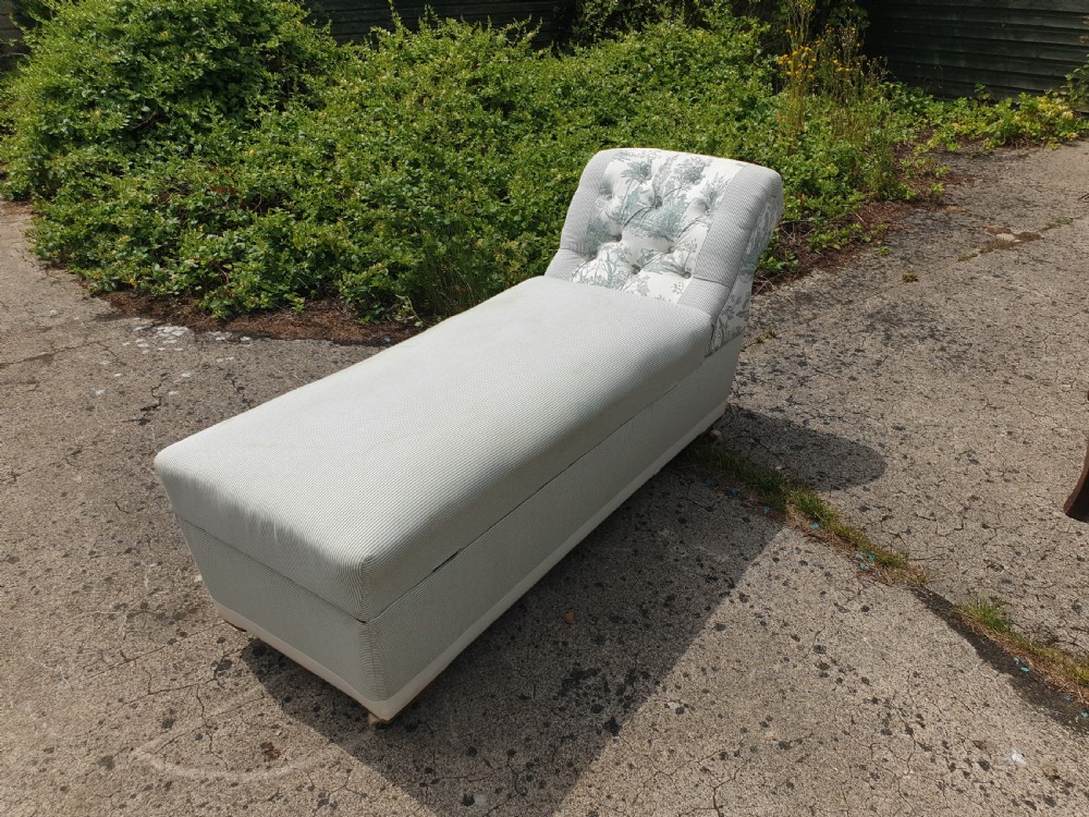 A late Victorian box ottoman chaise longue upholstered in grey and white ticking stripe fabric featuring a button-tufted backrest and a brass front latch. View V