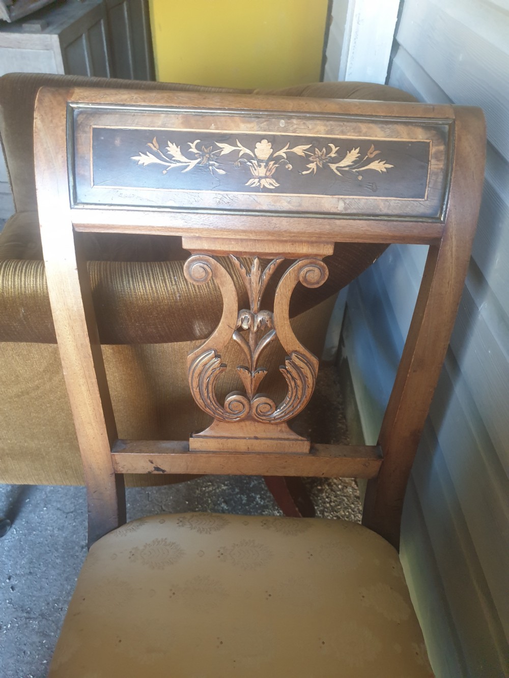 An antique wooden window seat featuring raised ends with lyre-carved splats, floral marquetry top rails, and a cream patterned upholstered cushion. View II