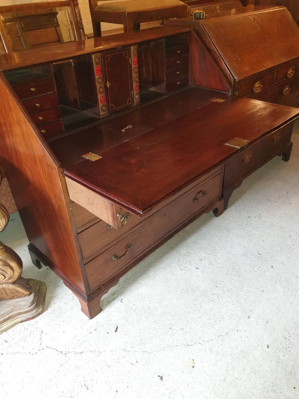 An early 19th century mahogany slant-front bureau featuring a fitted interior with small drawers and pigeonholes above two wide lower drawers with brass handles. View II