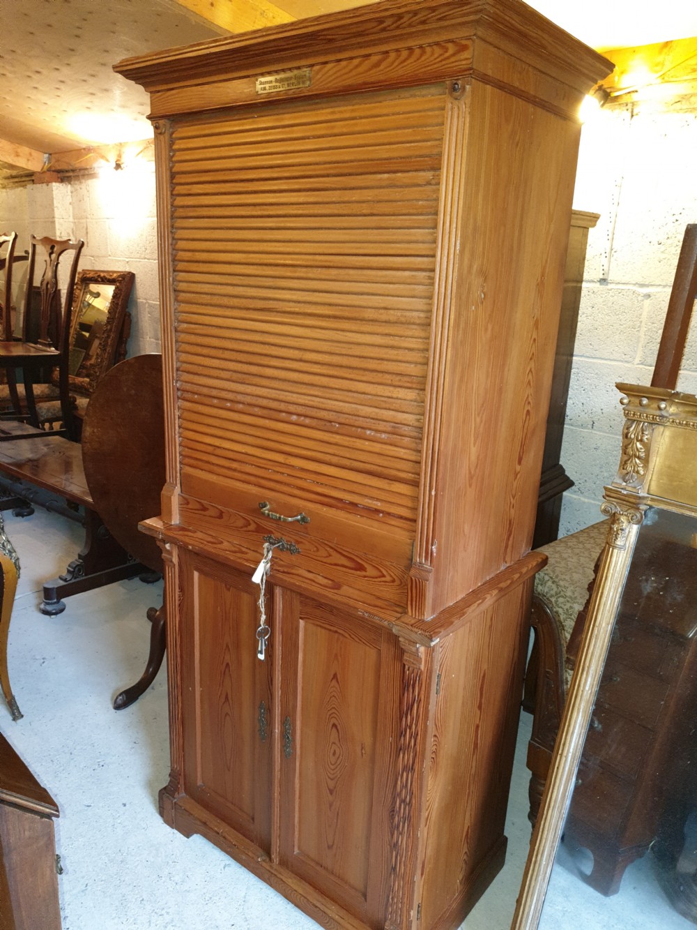 A tall Edwardian pine office cabinet featuring a slatted tambour roll shutter upper section above a two-door panelled lower cupboard.