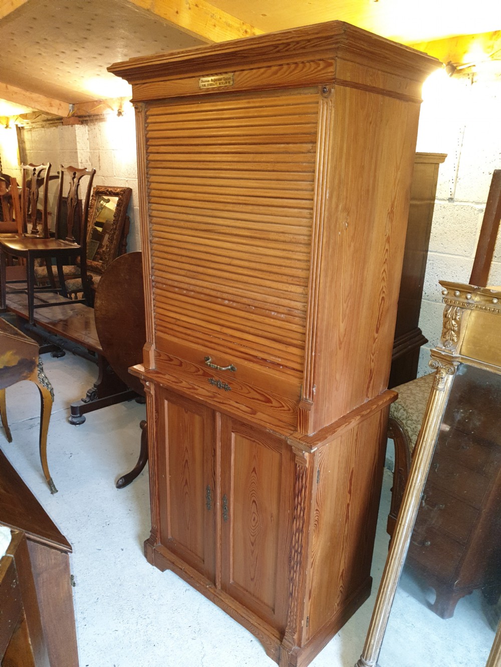 A tall Edwardian pine office cabinet featuring a slatted tambour roll shutter upper section above a two-door panelled lower cupboard. View VI