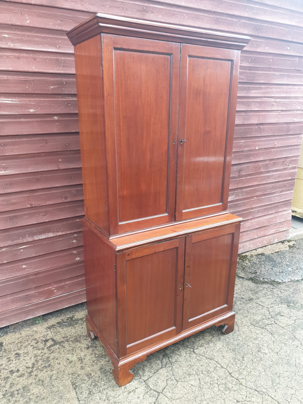 An early nineteenth-century mahogany fitted office cabinet featuring upper panel doors opening to internal pigeonholes and vertical dividers, above lower double cupboard doors on bracket feet. View III