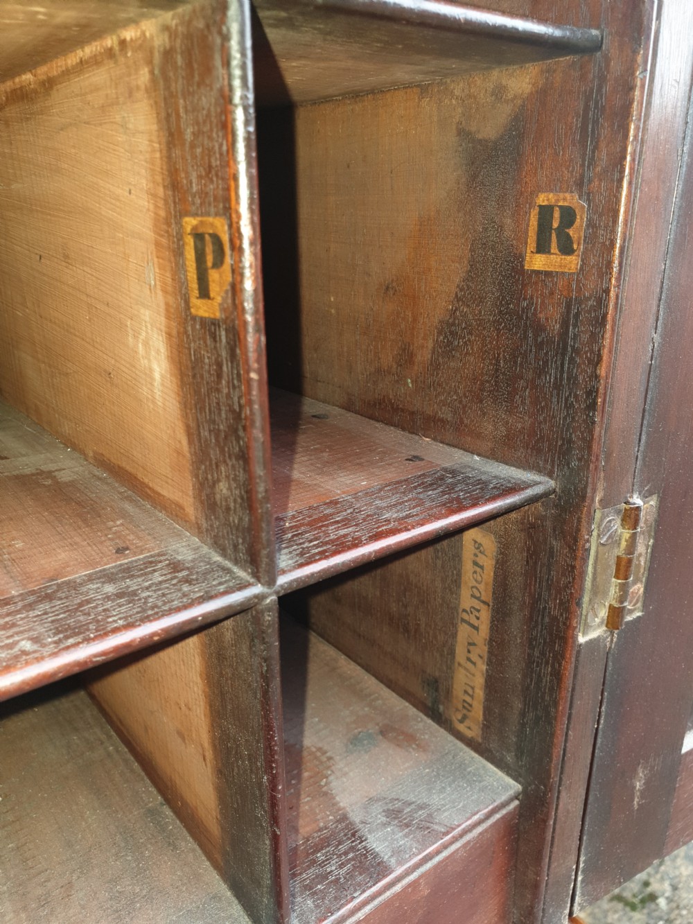 An early nineteenth-century mahogany fitted office cabinet featuring upper panel doors opening to internal pigeonholes and vertical dividers, above lower double cupboard doors on bracket feet. View IV