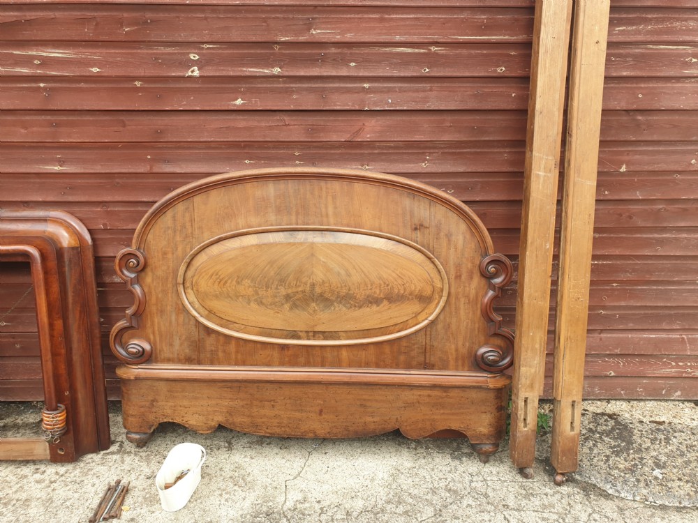 Dismantled mid-19th century mahogany half tester bed showing arched flame mahogany headboard, scroll carvings, side rails, and canopy timber framing. View III