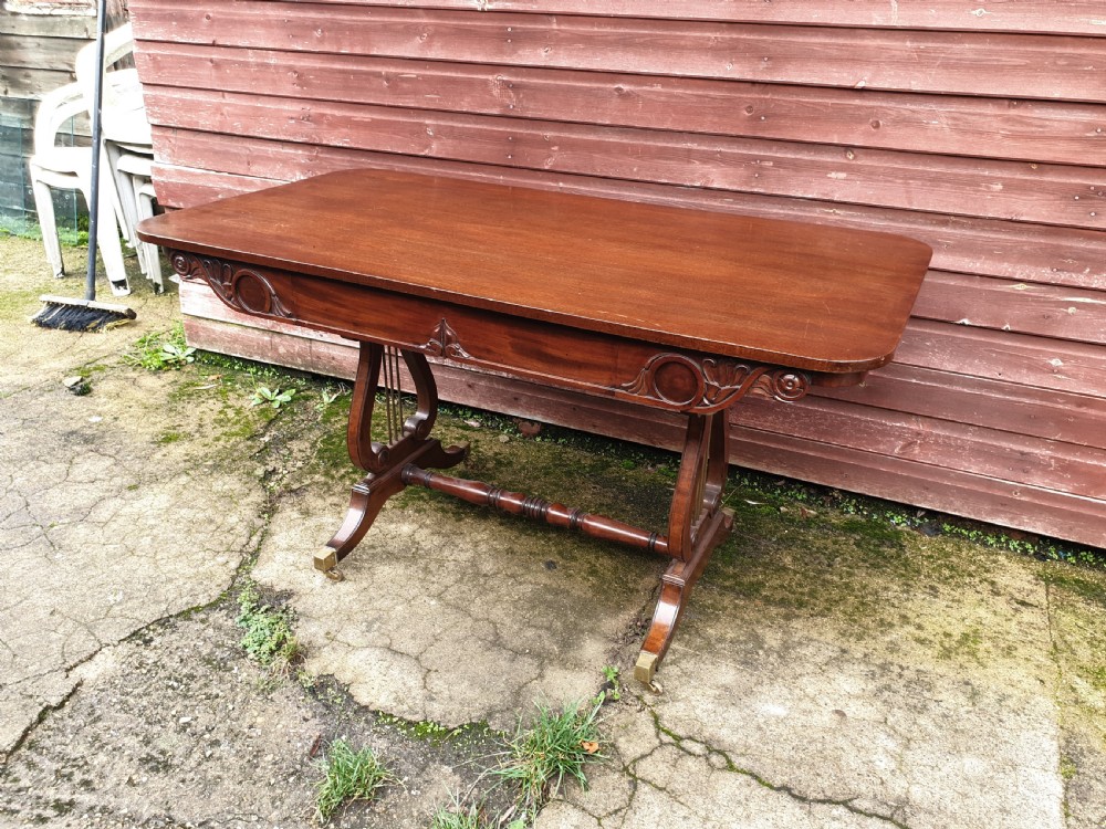 A 19th-century mahogany side table with an open single drawer, carved scroll frieze, lyre end supports, and brass castors. View V