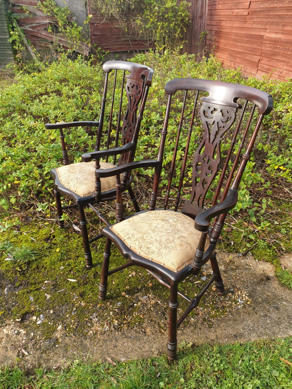 A pair of dark mahogany Edwardian hall armchairs featuring pierced carved back splats, turned spindle supports, curved armrests, and patterned upholstered seats with stud trim. View II