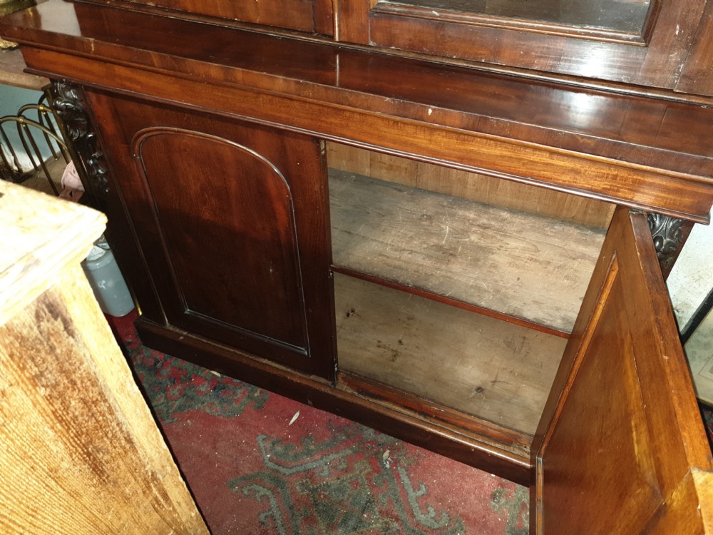 A mid-19th century Victorian mahogany two-part bookcase featuring a glazed upper cabinet with arched glass panes above a lower cupboard base. View V