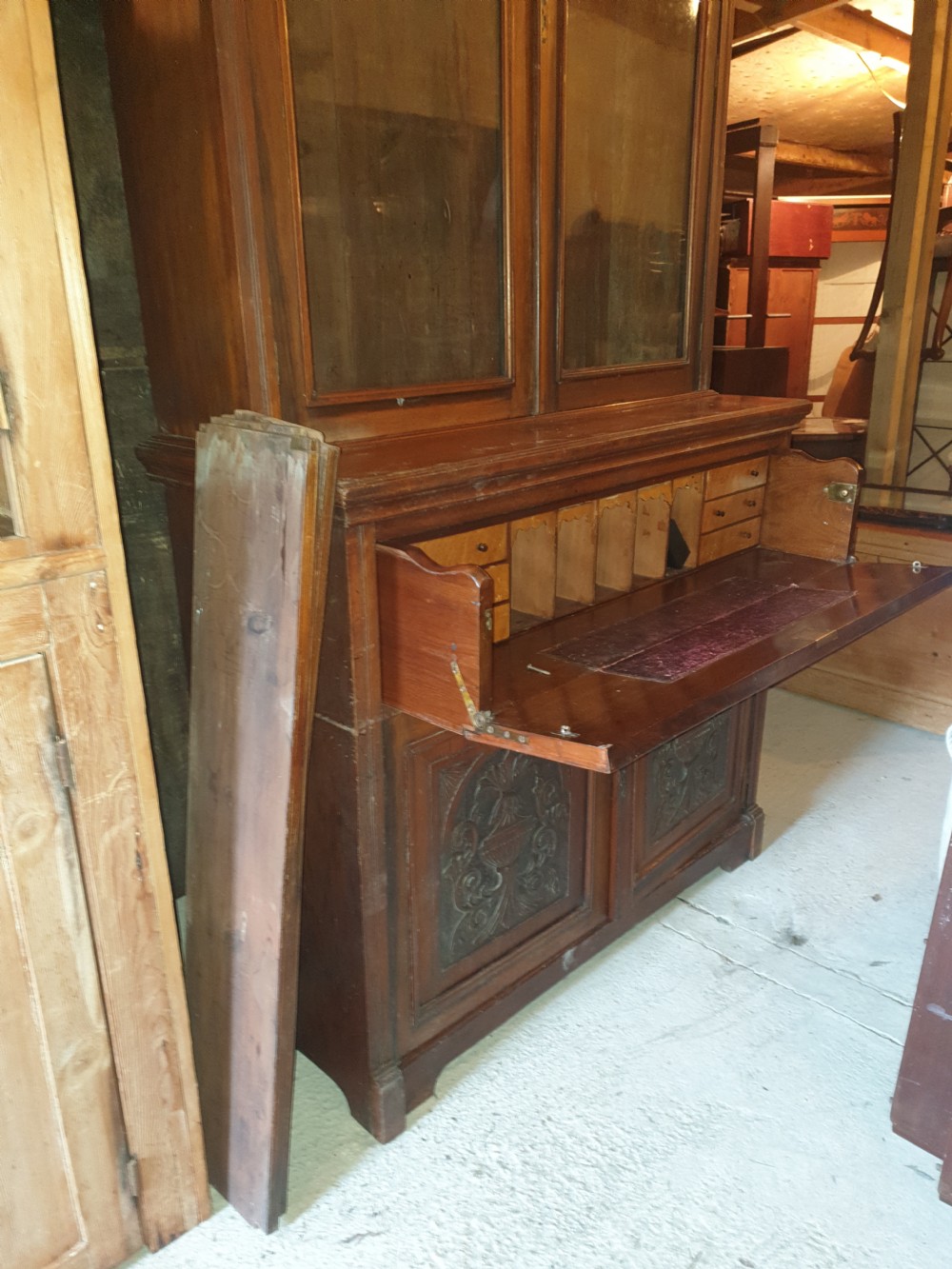 A late Victorian walnut secretaire bookcase featuring double glazed upper doors, a pull-out fitted writing drawer with interior compartments, and carved lower doors. View V