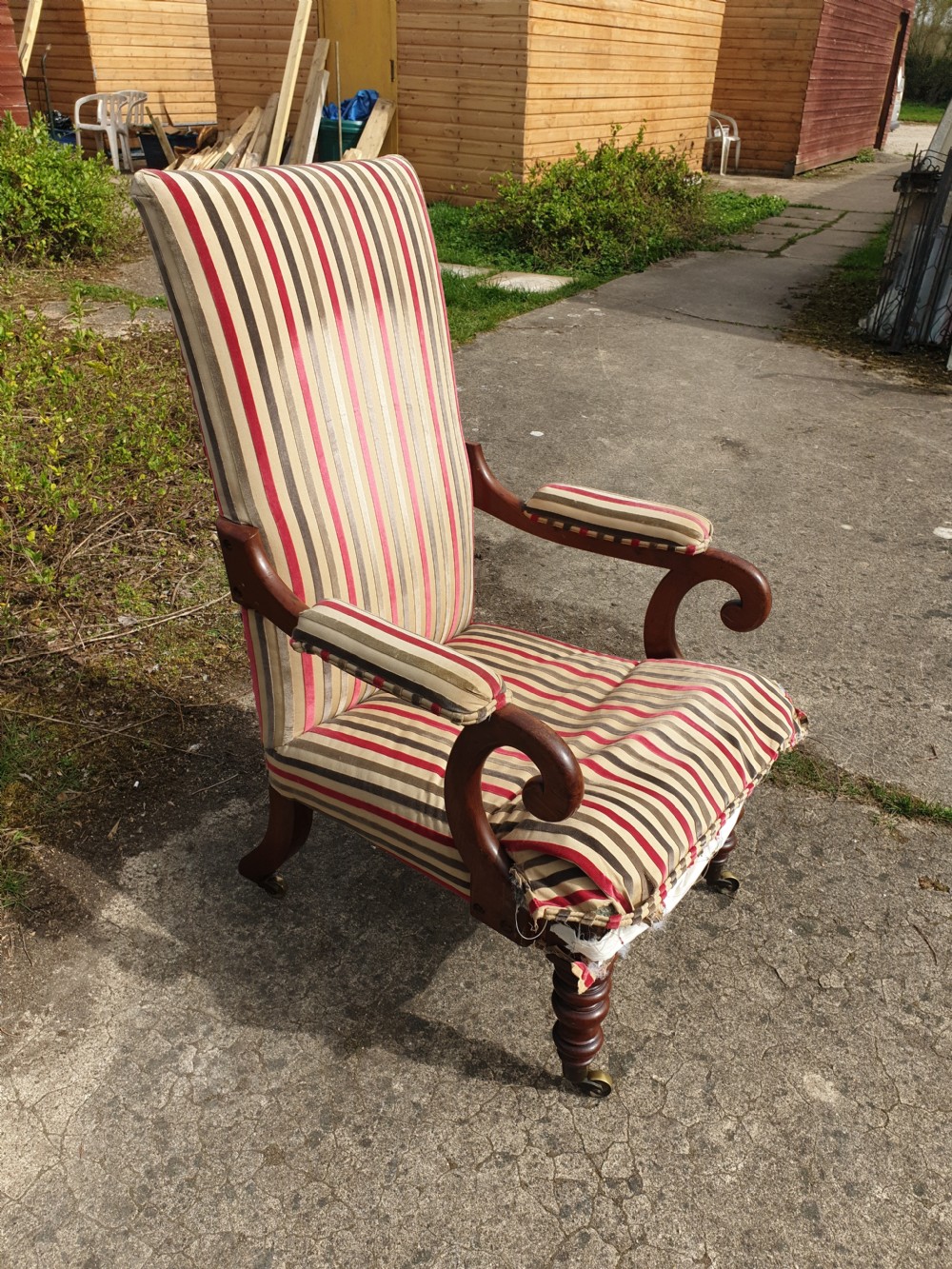 A Regency period mahogany armchair featuring a high backrest, padded scroll arms, striped fabric upholstery, and turned front legs on brass castors. View III