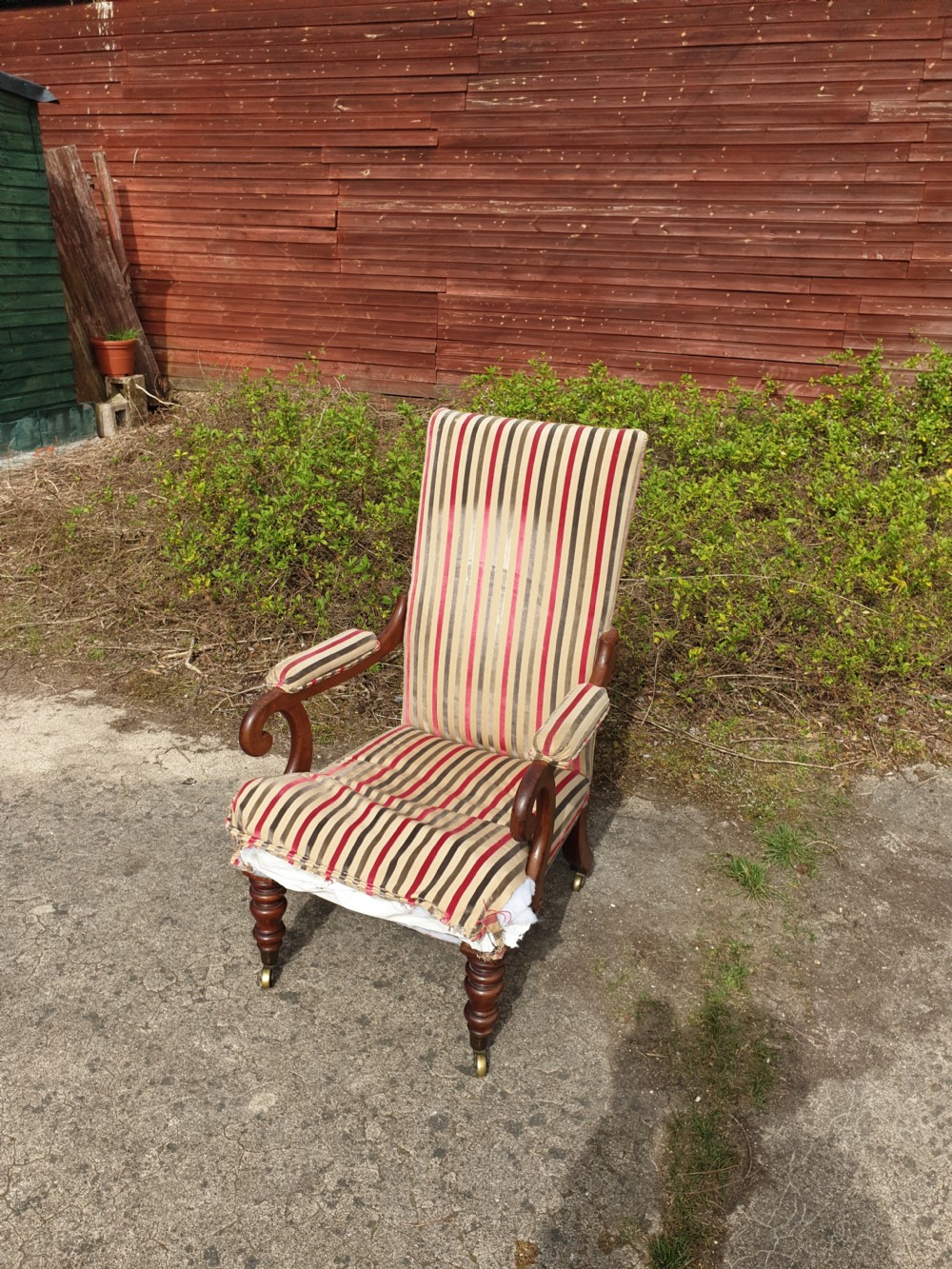 A Regency period mahogany armchair featuring a high backrest, padded scroll arms, striped fabric upholstery, and turned front legs on brass castors. View IV