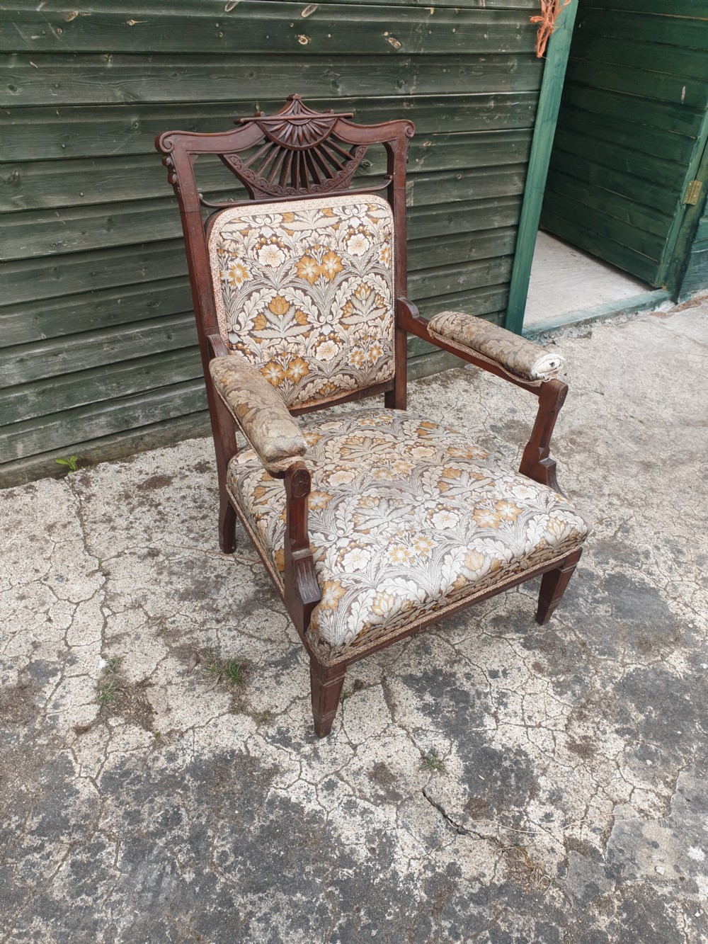 A late Victorian mahogany armchair featuring a carved openwork sunburst cresting rail, upholstered back panel and seat in a floral pattern, and padded armrests. View III