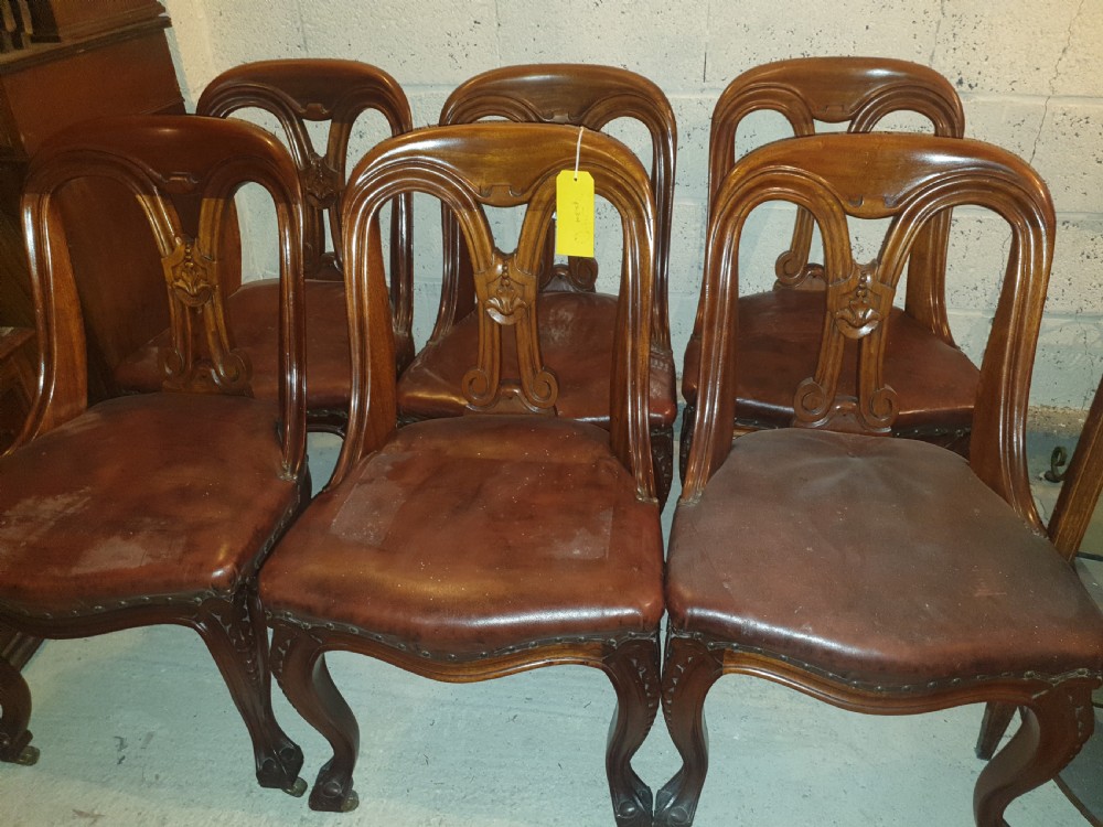 A set of six Victorian carved mahogany dining chairs featuring balloon backs, carved central splats, brown leather seats, and cabriole front legs. View II