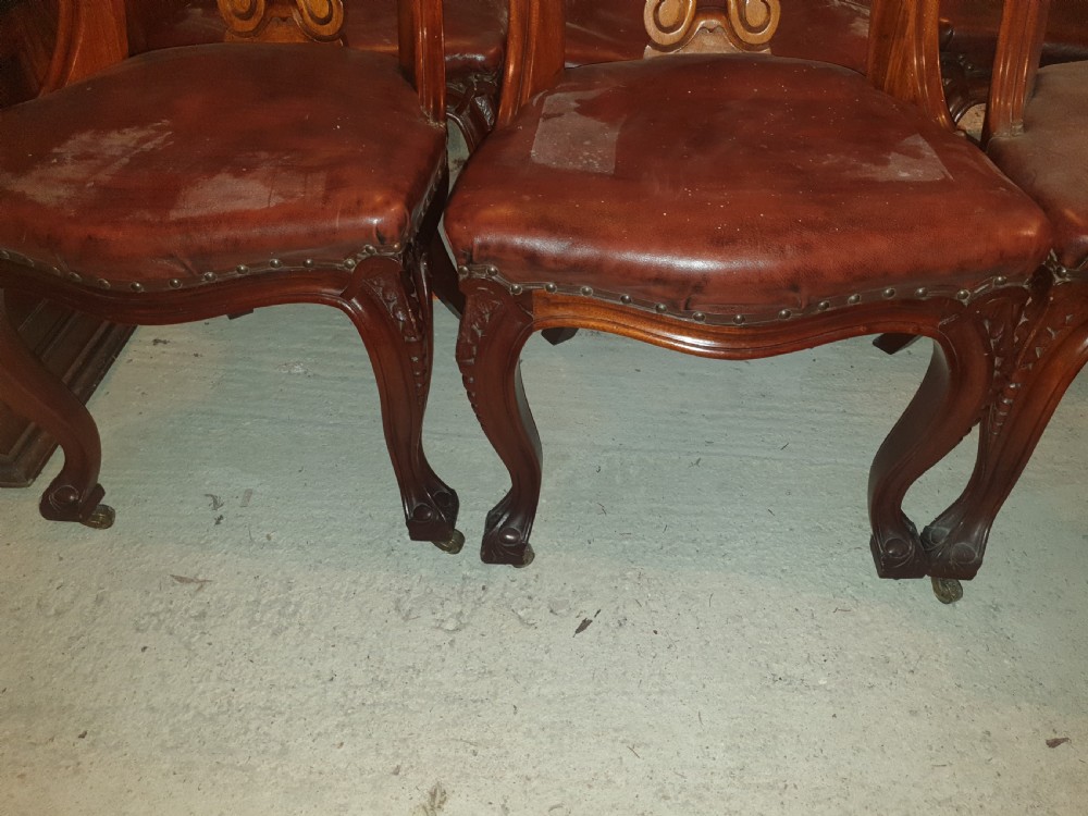 A set of six Victorian carved mahogany dining chairs featuring balloon backs, carved central splats, brown leather seats, and cabriole front legs. View III