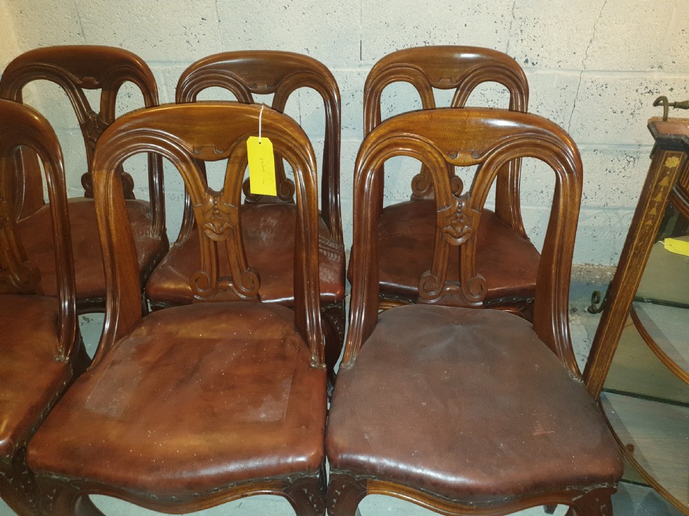 A set of six Victorian carved mahogany dining chairs featuring balloon backs, carved central splats, brown leather seats, and cabriole front legs. View IV