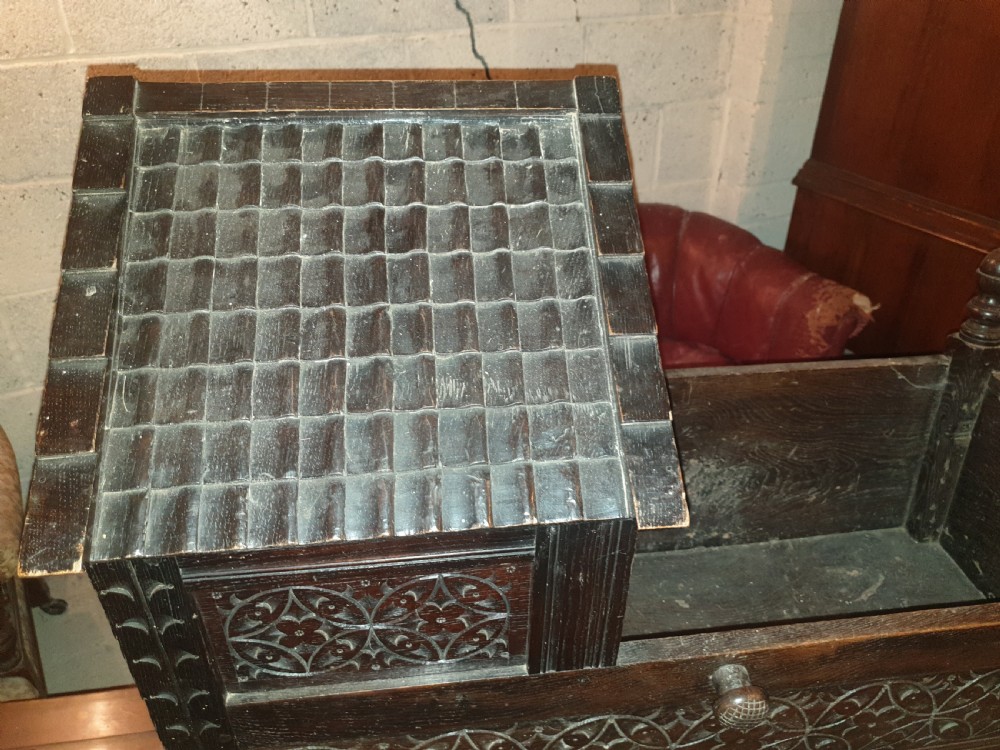 A dark carved oak Victorian rocking cradle featuring a tiled wooden hood, geometric floral carving, and turned finials. View II