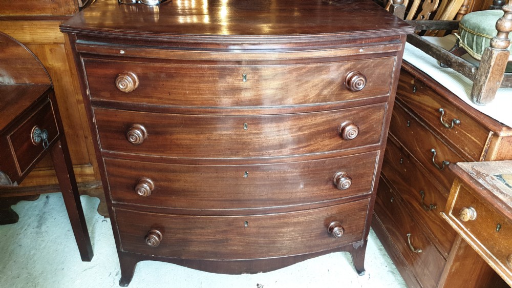 A Regency mahogany bowfront chest of drawers featuring four graduated drawers with turned wooden handles and a brushing slide, supported by splayed feet. View VIII