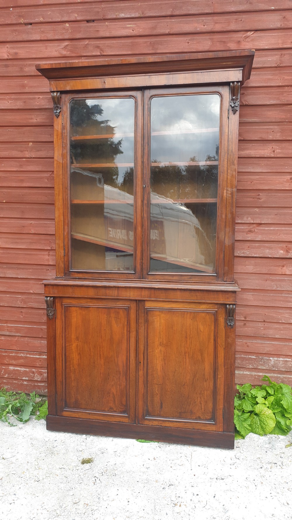 A tall Victorian two-part mahogany library bookcase featuring an upper glass-front cabinet over a solid two-door panelled cupboard base.