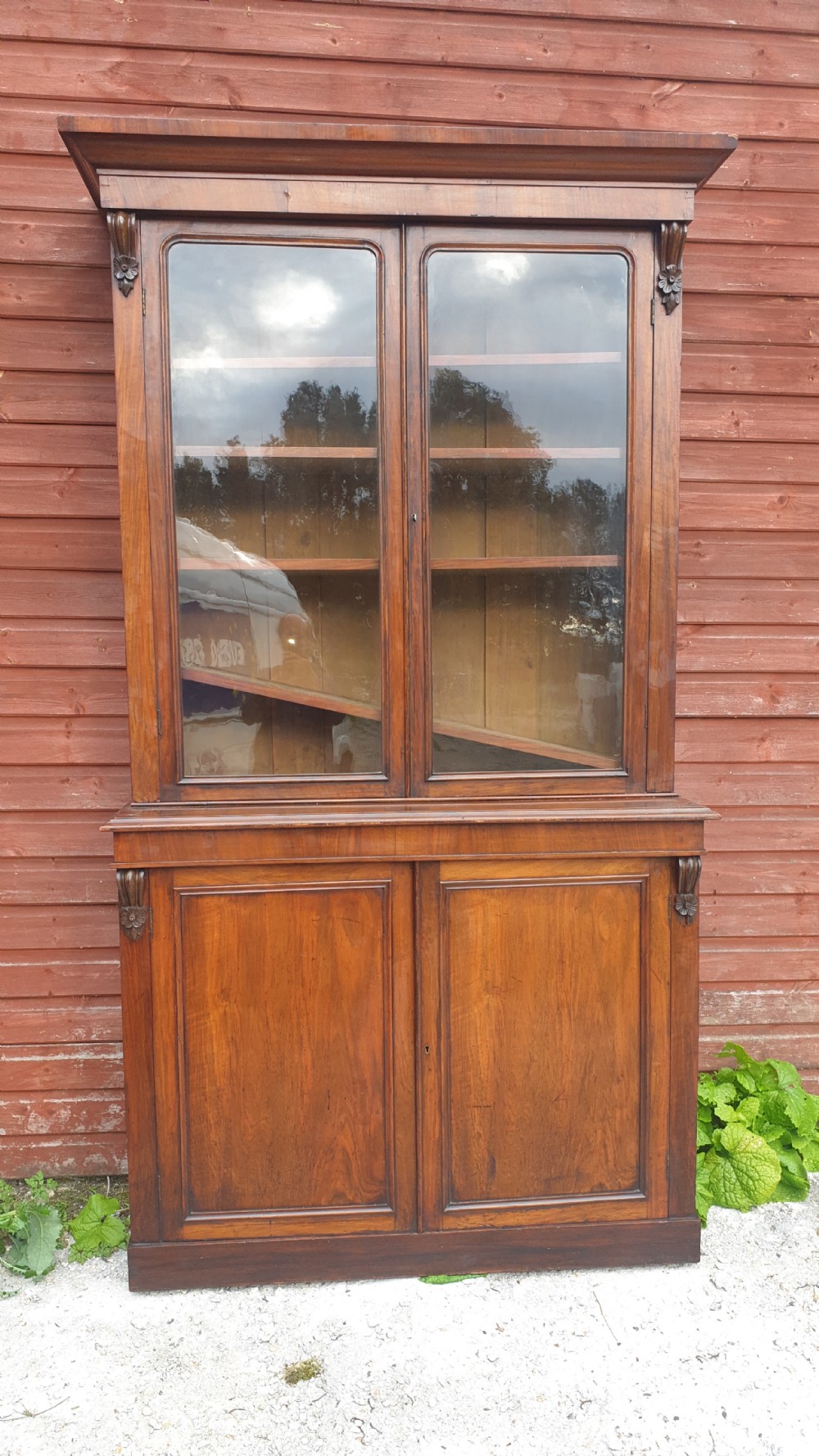 A tall Victorian two-part mahogany library bookcase featuring an upper glass-front cabinet over a solid two-door panelled cupboard base. View IV
