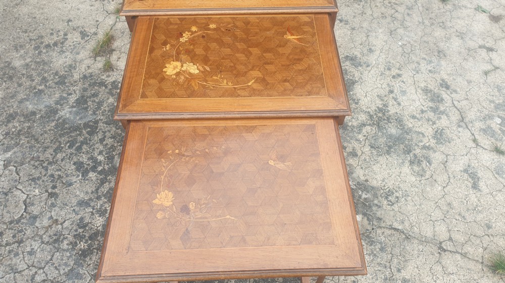 A set of three graduated wooden nesting tables featuring geometric parquetry tops inlaid with delicate floral and bird motifs. View V
