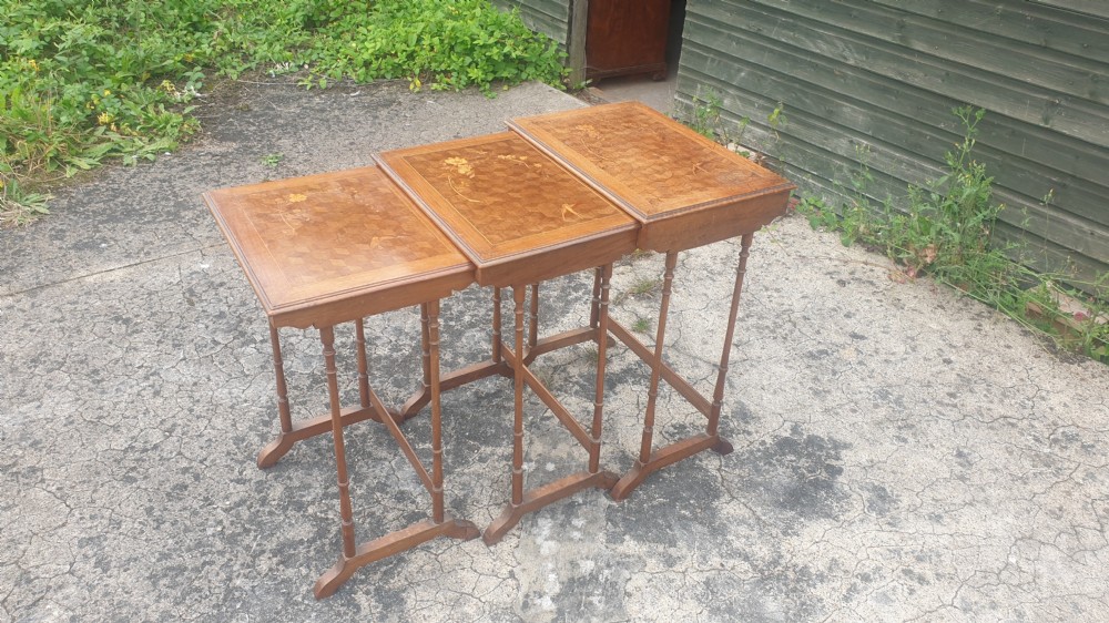 A set of three graduated wooden nesting tables featuring geometric parquetry tops inlaid with delicate floral and bird motifs. View VII
