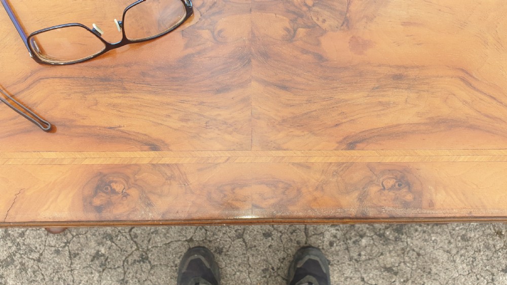 A Queen Anne style walnut side table featuring a figured veneer top, three drawers with brass handles, an arched apron, and four cabriole legs resting on pad feet. View III