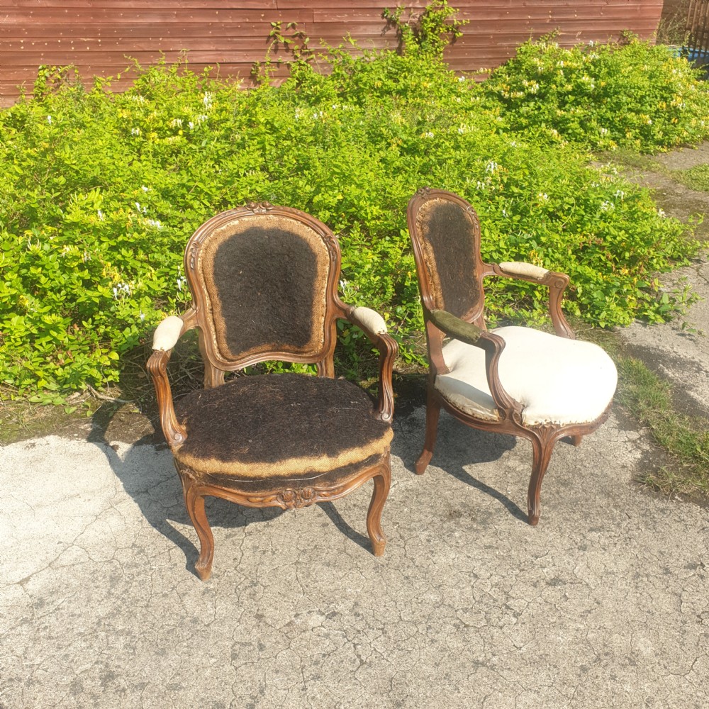 A pair of antique French Louis XV style carved wooden fauteuil armchairs stripped back to their padding and hessian foundation.