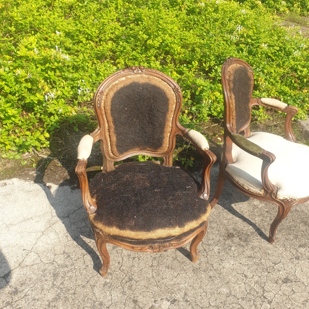A pair of antique French Louis XV style carved wooden fauteuil armchairs stripped back to their padding and hessian foundation. View II