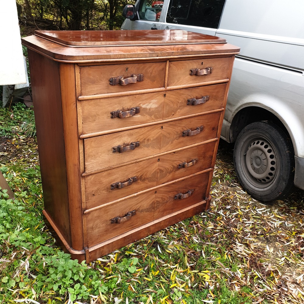 A large Victorian mahogany chest of drawers featuring two short over four long graduated drawers with carved wooden handles and a plinth base.