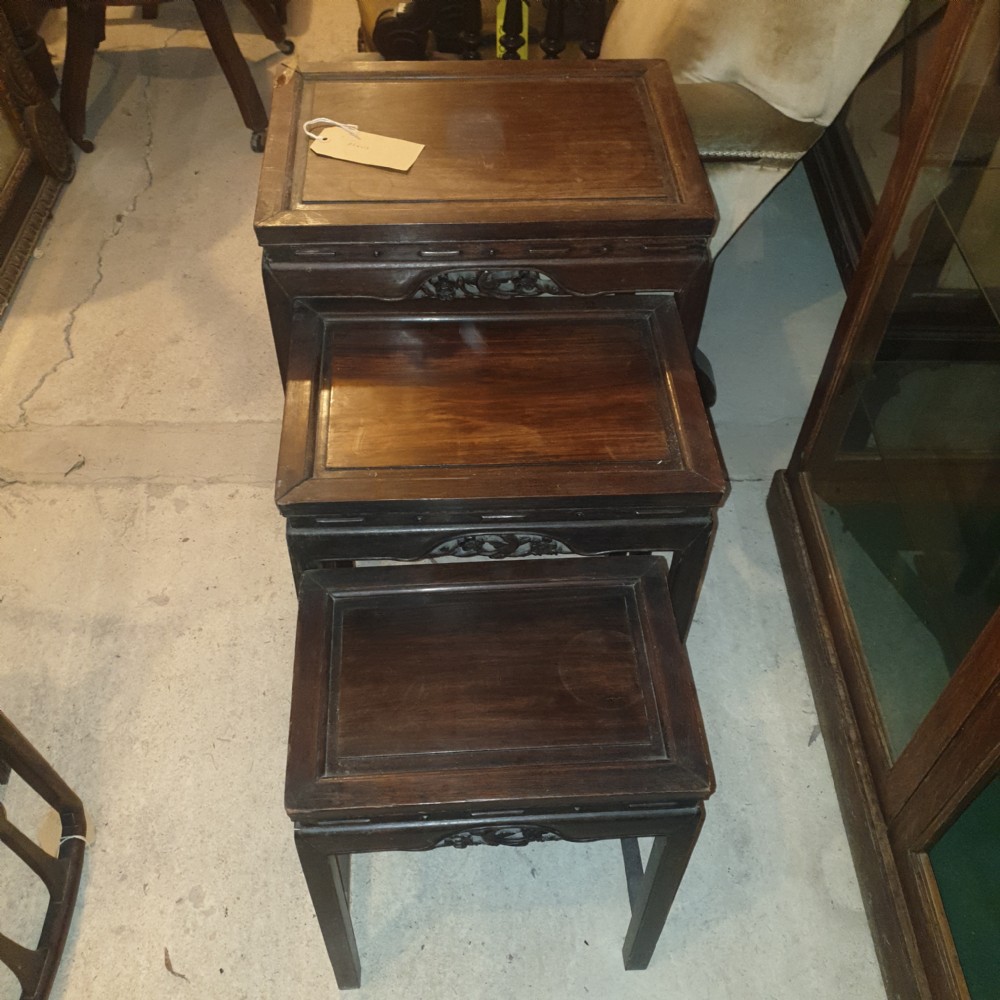 A set of three nested dark hardwood Chinese side tables with carved floral aprons and stepped rectangular tops. View II