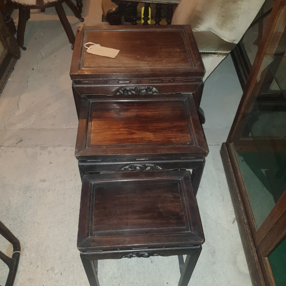 A set of three nested dark hardwood Chinese side tables with carved floral aprons and stepped rectangular tops. View III