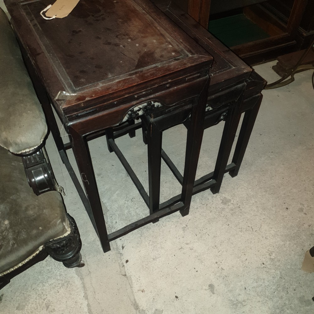 A set of three nested dark hardwood Chinese side tables with carved floral aprons and stepped rectangular tops. View V
