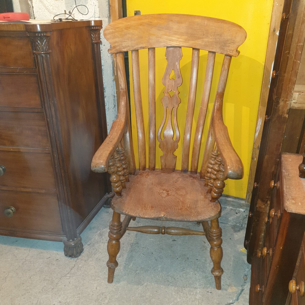 A Victorian farmhouse Windsor armchair made of timber featuring a shaped crest rail, pierced central splat, turned legs, and contoured seat. View IV