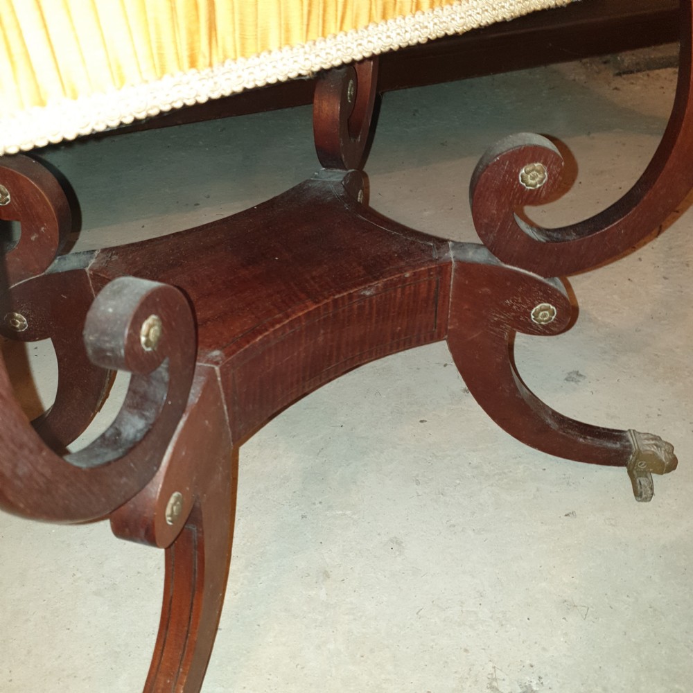 An antique Regency mahogany sewing table featuring inlaid drawers, a pleated fabric work basket, and swept legs with brass castors. View V