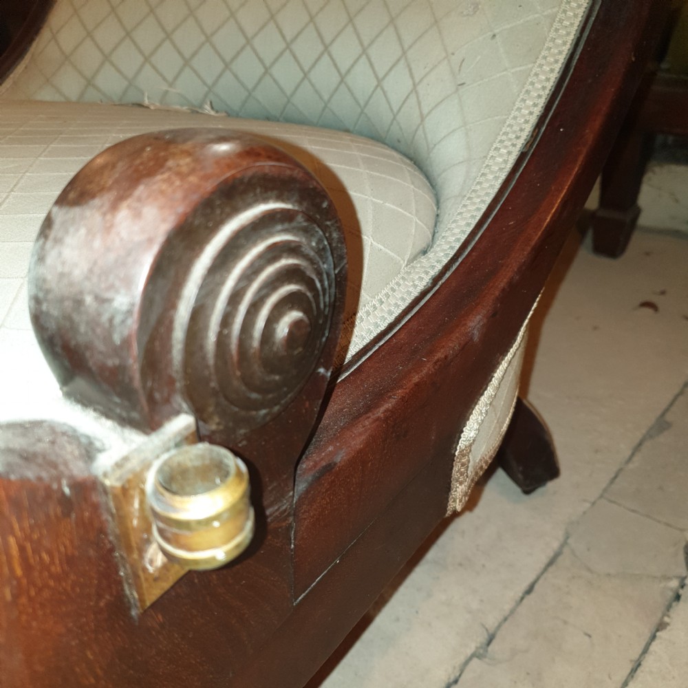 Early Victorian mahogany library armchair featuring button-tufted light upholstery, scrolled padded arms, turned front legs, and brass castors. View III