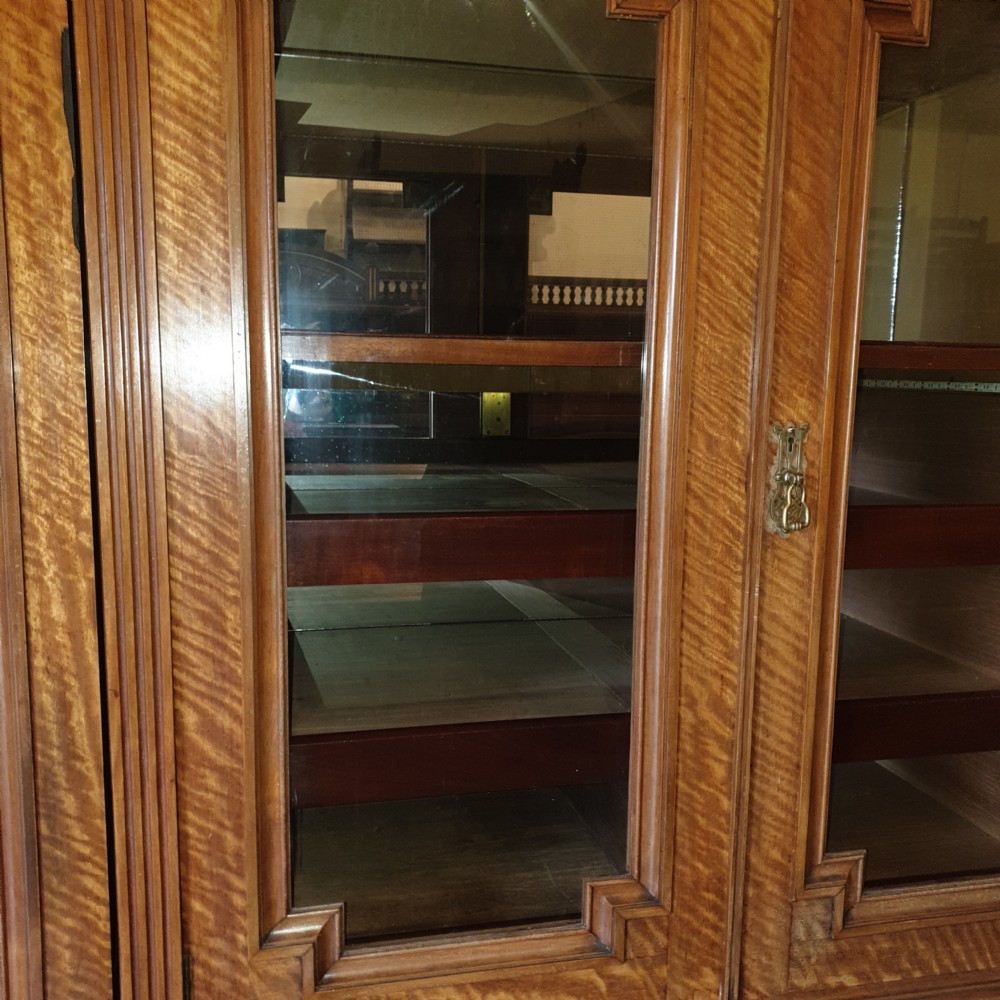 An Edwardian satinwood triple wardrobe featuring mirrored side doors, a central upper compartment, five drawers, and a stepped cornice top. View IX