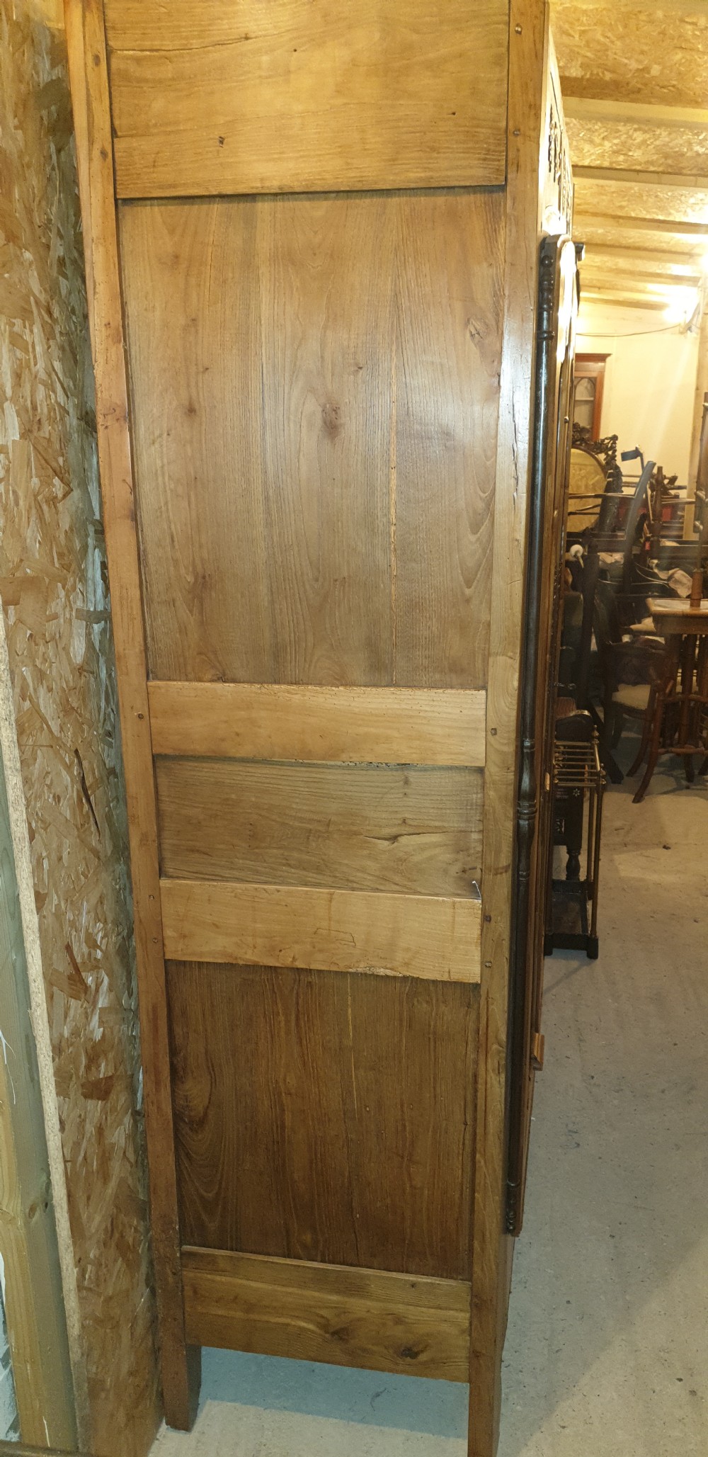A tall French oak armoire featuring double panel doors decorated with carved floral motifs and long iron escutcheons. View II