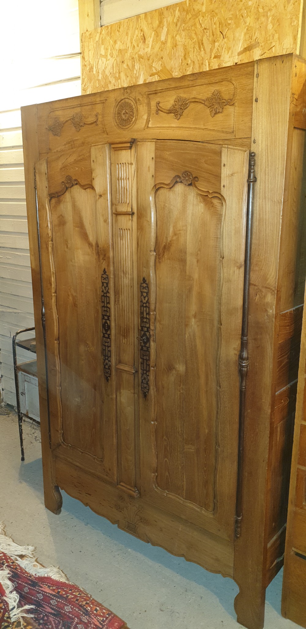 A tall French oak armoire featuring double panel doors decorated with carved floral motifs and long iron escutcheons. View III