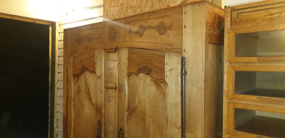 A tall French oak armoire featuring double panel doors decorated with carved floral motifs and long iron escutcheons. View VII