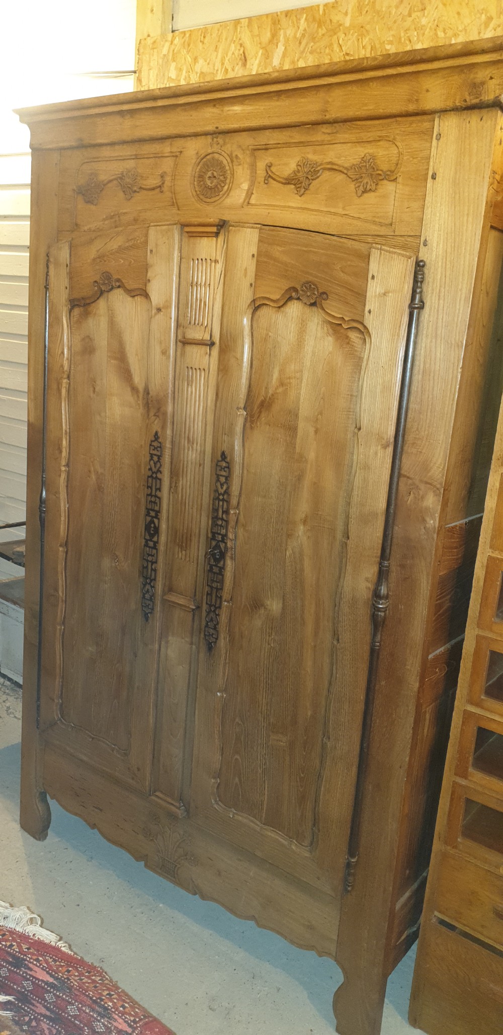A tall French oak armoire featuring double panel doors decorated with carved floral motifs and long iron escutcheons. View VIII