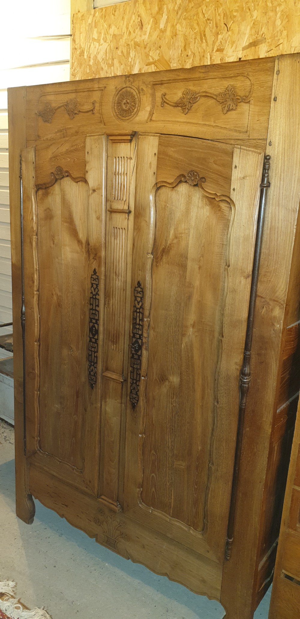 A tall French oak armoire featuring double panel doors decorated with carved floral motifs and long iron escutcheons. View IX