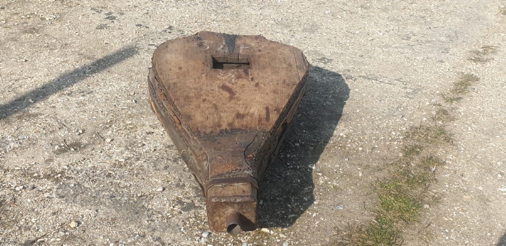 An antique blacksmith bellows converted into a low coffee table with timber boards, riveted leather sides, and wooden feet. View II