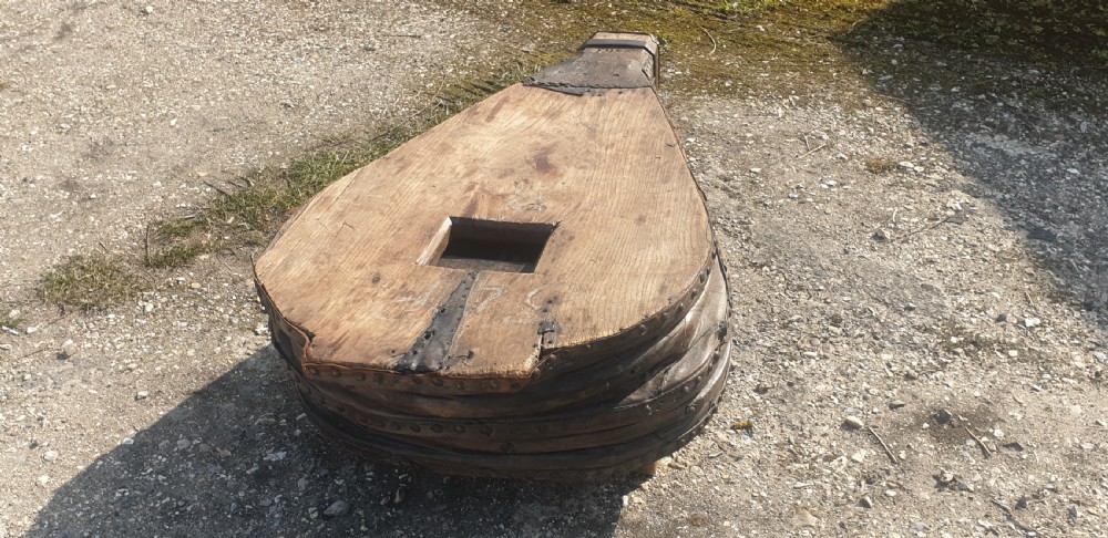 An antique blacksmith bellows converted into a low coffee table with timber boards, riveted leather sides, and wooden feet. View IV