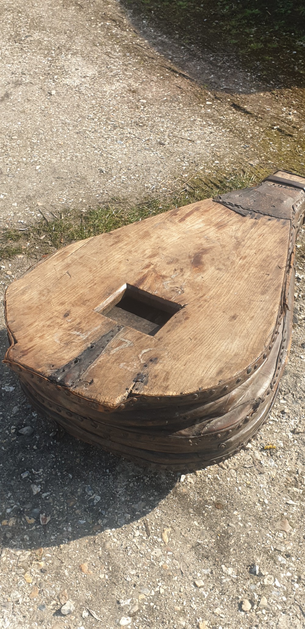 An antique blacksmith bellows converted into a low coffee table with timber boards, riveted leather sides, and wooden feet. View VI