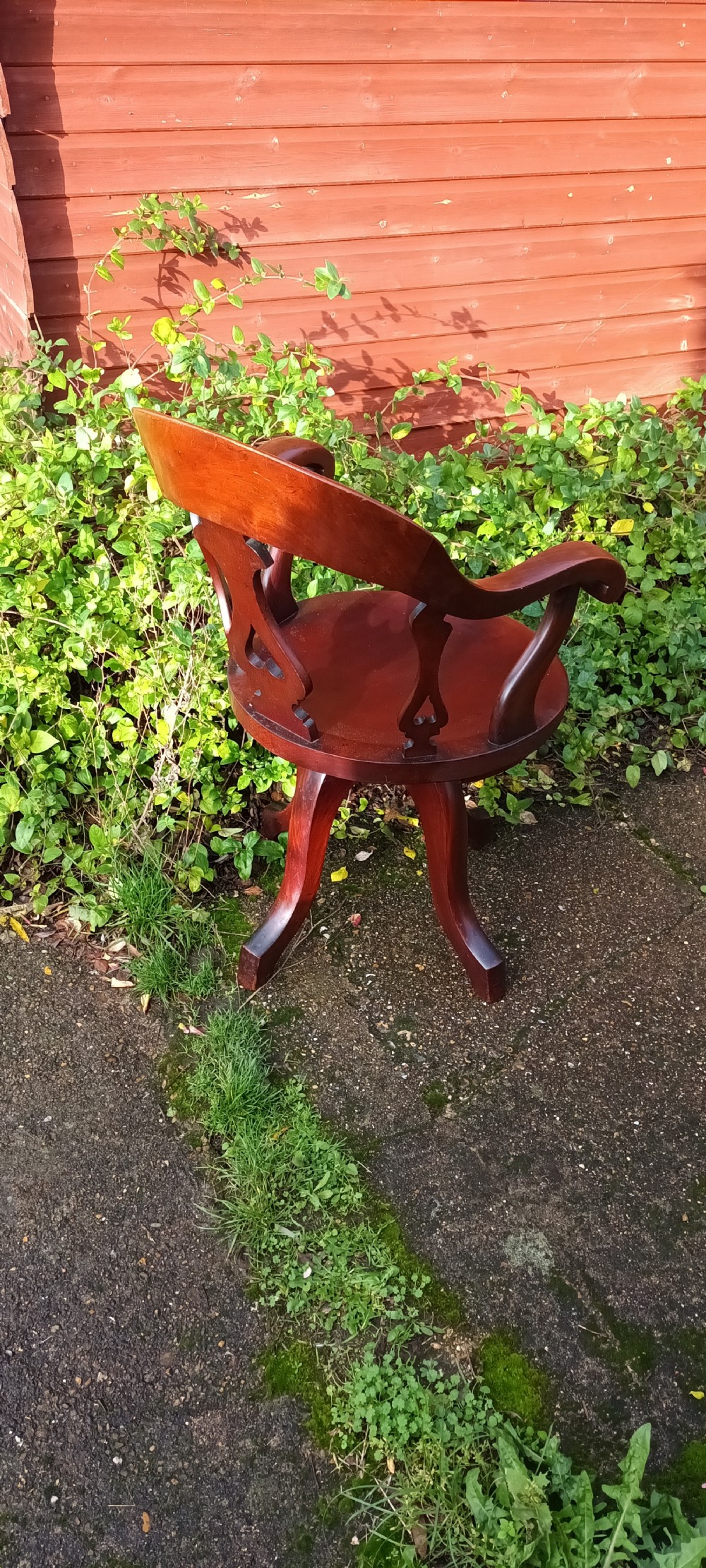 A late Victorian reddish-brown mahogany revolving desk armchair featuring a curved backrest with a pierced splat and a solid wooden seat resting on a swivel base. View III